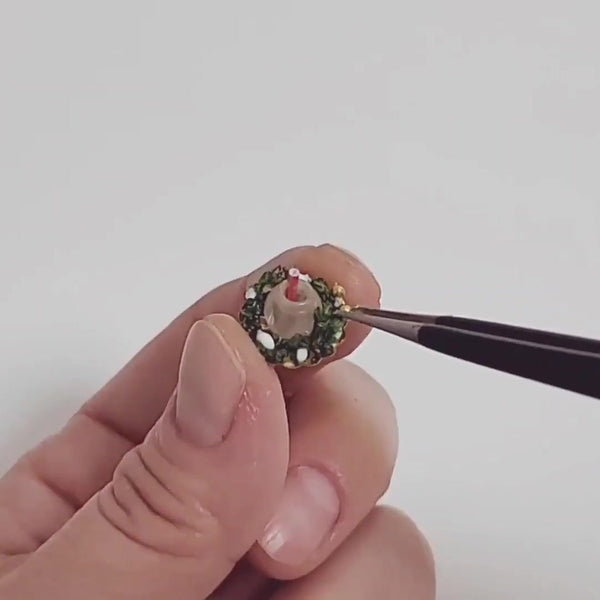 Holding a tiny Christmas wreath with tweezers